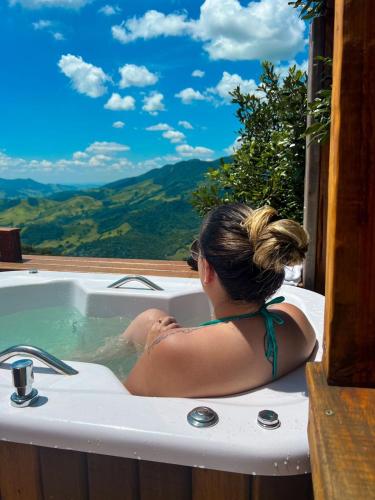 a woman sitting in a bath tub with a view at Cabanas Bela Vista in São Bento do Sapucaí