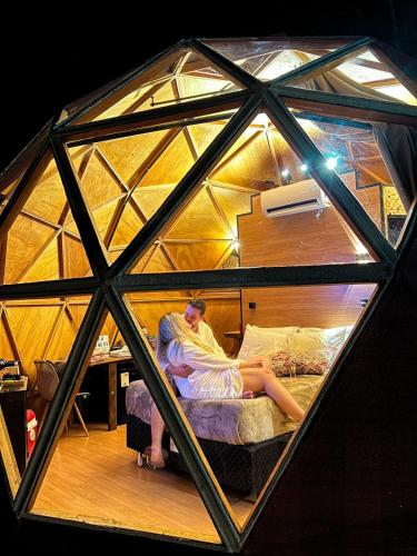 a man laying on a bed in a glass igloo at Cabanas Bela Vista in São Bento do Sapucaí