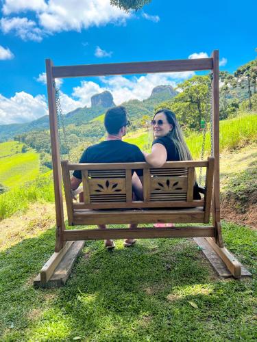 a man and a woman sitting on a swing at Cabanas Bela Vista in São Bento do Sapucaí