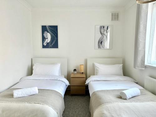 two twin beds in a room with white walls at Deducted 3B Flat, Fast Wi-Fi, 5 min Canning Town, near ExCel & O2 in London