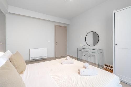 a white bedroom with a bed and a mirror at SuiteHome Villas with Private Pools by Explore Andros in Andros