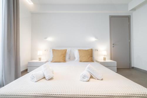 a white bedroom with two beds with towels on them at SuiteHome Villas with Private Pools by Explore Andros in Andros