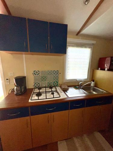 Il comprend une petite cuisine équipée d'une cuisinière et d'un évier. dans l'établissement Mobilhome Île d Oléron Camping Les Tamaris, à Saint-Pierre-dʼOléron