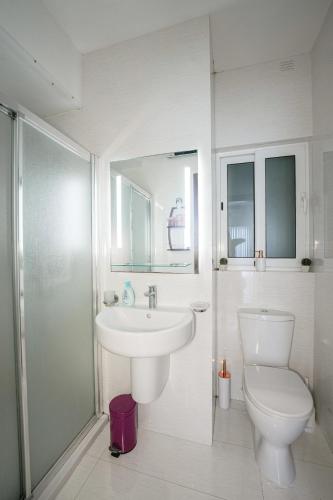 a white bathroom with a sink and a toilet at Seaview flat in Mellieha's heart in Is-Sellum