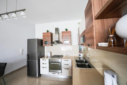 a kitchen with a refrigerator and a stove top oven at Seaview flat in Mellieha's heart in Is-Sellum