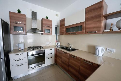 a kitchen with wooden cabinets and a stove top oven at Seaview flat in Mellieha's heart in Is-Sellum