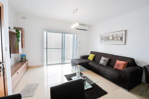 a living room with a black couch and a table at Seaview flat in Mellieha's heart in Is-Sellum