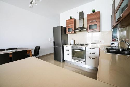 a kitchen with a stainless steel refrigerator and a table at Seaview flat in Mellieha's heart in Is-Sellum