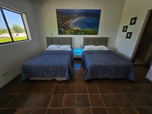 two beds in a room with a view of the ocean at Nica Valley in Rivas