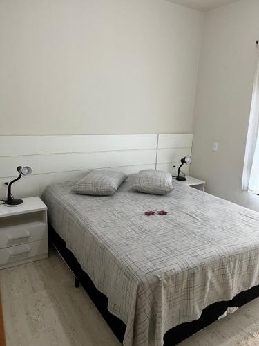 a bedroom with a bed with two lamps on it at Garopaba - Praia da Gamboa - Apartamento com piscina in Garopaba