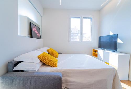 a bedroom with a bed with yellow pillows and a tv at BRERA LittleSuite DuomoView in Milan