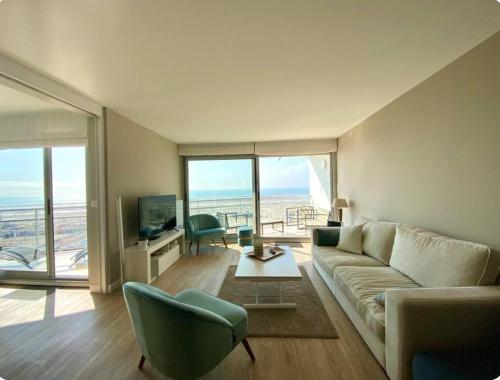 un salon avec un canapé, des chaises et une télévision dans l'établissement Le Front de mer - Centre-ville - Vue mer - Parking gratuit, à Le Touquet-Paris-Plage