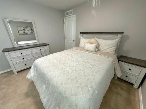 ein Schlafzimmer mit einem weißen Bett mit zwei Kommoden und einem Spiegel in der Unterkunft Jeanell's Place in Davenport