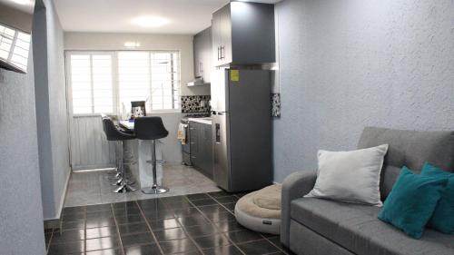 a living room with a couch and a kitchen at Comodo apartamento de 3 habitaciones, a 10 min en vehiculo del Zocalo de Oaxaca in Oaxaca City