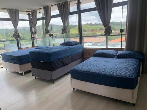 two beds in a room with a large window at Chácara de alto padrão in Água Boa