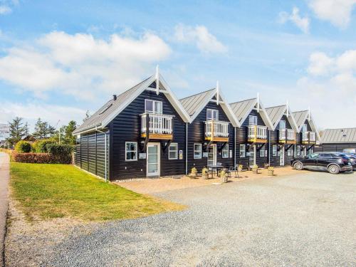a black house with a car parked in front of it at 4 person holiday home in Blåvand in Blåvand
