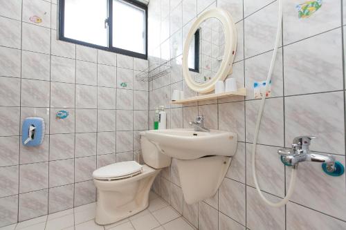 a bathroom with a sink and a toilet and a mirror at Time Travelodge Homestay in Zhuangwei
