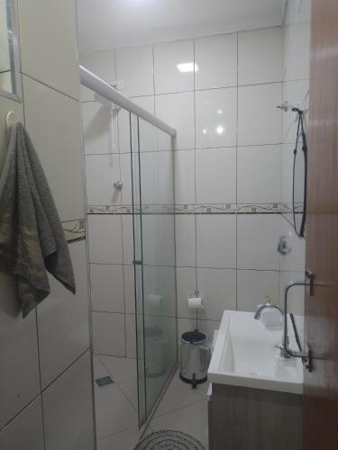 a bathroom with a glass shower and a sink at Casa completa a 10 min do aeroporto Guarulhos in Guarulhos