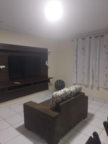 a living room with a couch and a flat screen tv at Casa completa a 10 min do aeroporto Guarulhos in Guarulhos