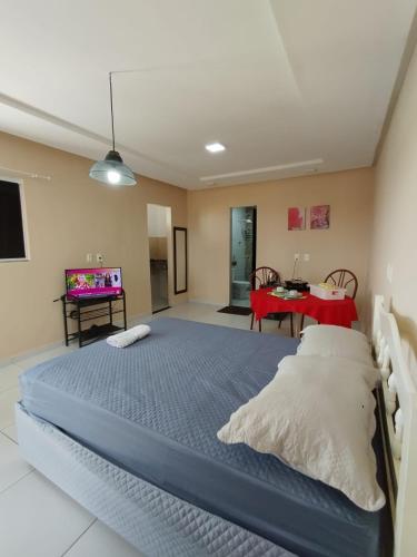ein Schlafzimmer mit einem großen Bett und einem Tisch in der Unterkunft Kitnet 2 com varanda in Mossoró