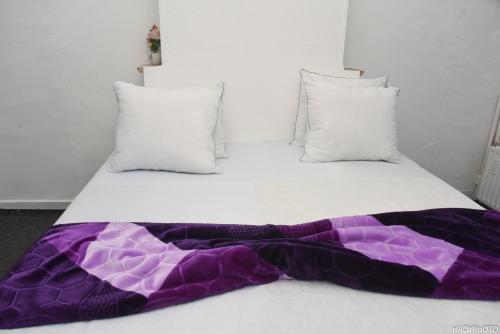 a white bed with a purple blanket on it at Hébergement confort Garé de l'ouest in Brussels
