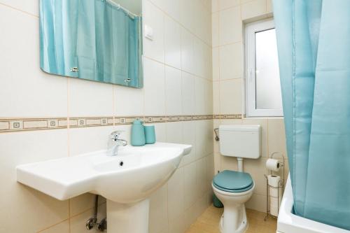 a bathroom with a sink and a toilet and a mirror at Apartmani F&M in Kotor
