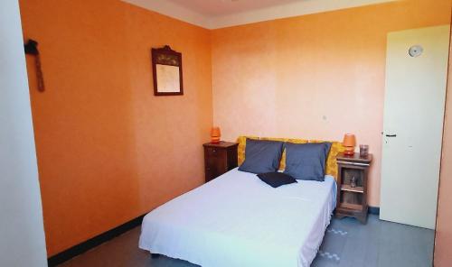 une chambre avec un lit blanc et un mur orange dans l'établissement L'Andronne, à Vallon-Pont-dʼArc