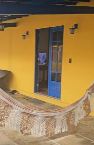 a yellow building with a blue door and a bench at CASA COLONIAL Ilha da Croa in Barra de Santo Antônio