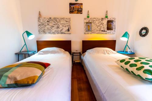 two twin beds in a room with two lamps at epicenter SKYBAR in Lagoa