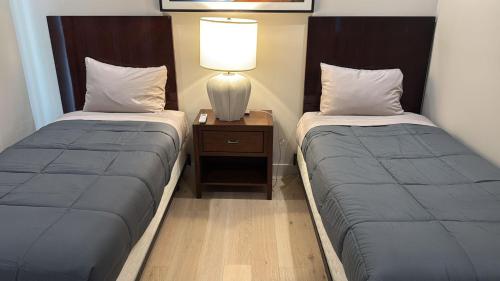 two beds in a room with a lamp on a night stand at Stylish Urban Escape in Downtown Los Angeles in Los Angeles