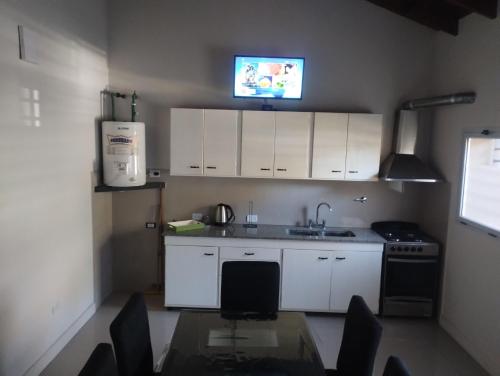a kitchen with white cabinets and a table and a tv at Adrogué Apart B in Adrogue
