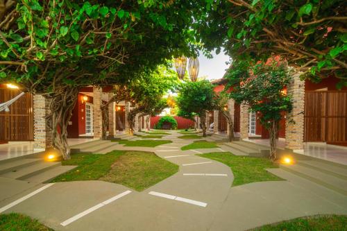 a walkway with trees and lights in a building at Pousada Arte do Velejo by Solarium in São Miguel do Gostoso