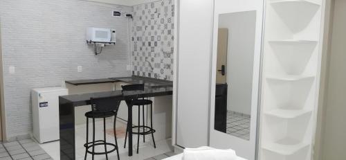 una pequeña cocina con encimera negra y taburetes en Ap Central Master 02, en Campina Grande
