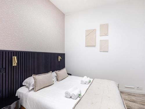 une chambre avec un lit avec des draps blancs et des oreillers dans l'établissement Superb Apartment Invalides St Germain des Près, à Paris