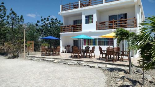 a building with chairs and tables and umbrellas at Popoyo Beach Home in Tola
