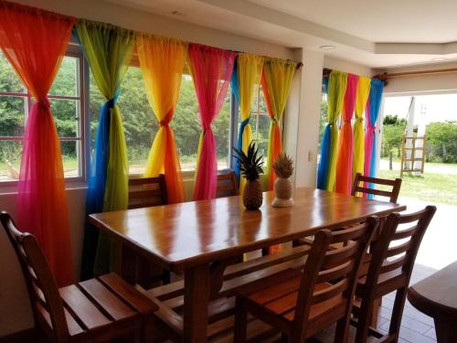 a dining room with a wooden table and colorful curtains at Popoyo Beach Home in Tola