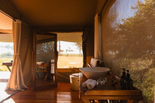 a bathroom with a bowl on a table in a tent at Enkusero Mara in Aitong