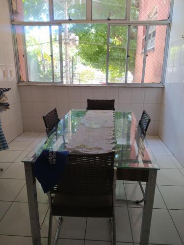 einen Glastisch und Stühle in einem Zimmer mit Fenstern in der Unterkunft Centro - Perto de tudo in Salvador