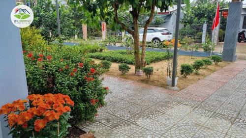 a garden with orange flowers and a sidewalk at YÊN Homestay in Dien Ban