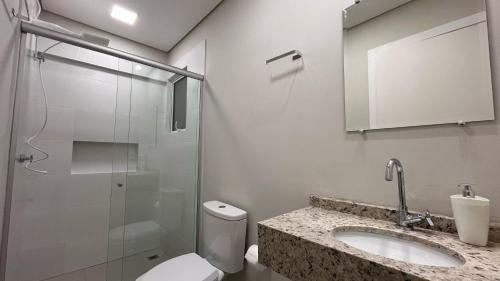 a bathroom with a toilet and a sink and a shower at Apartamento Perto do Centro Vaga de Garagem in Foz do Iguaçu