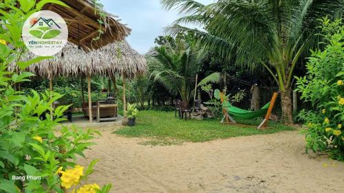 a resort with a hammock and some palm trees at YÊN Homestay in Dien Ban