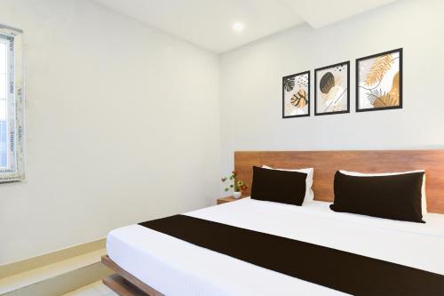 a bedroom with a white bed with black and white pillows at Super Hotel O Vaishnavi Residency in Hyderabad