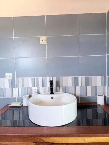 a white sink in a bathroom with blue tiles at Maison villa la faveur in Ngaparou