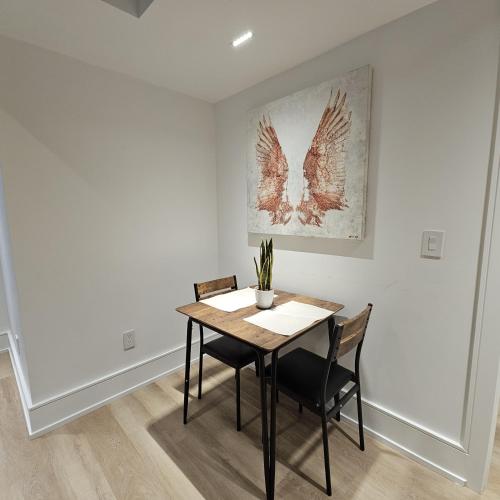 a dining room table with two chairs and a painting at Spacious Bright 9ft Ceiling with Private Entrance in Milton