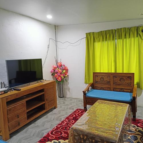 a living room with a flat screen tv and a couch at Raniah Homestay 2 in Gua Sai