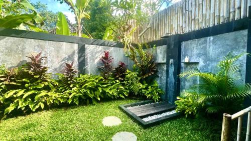 a garden with a wooden bench in front of a fence at Kubu Damai Guest House in Jatiluwih