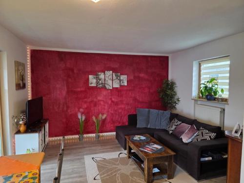 a living room with a couch and a red wall at Ferienwohnung Erika in Marquartstein