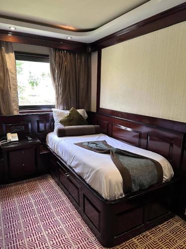 a bedroom with a large wooden bed with a window at فندق ريفر المعادي in Cairo