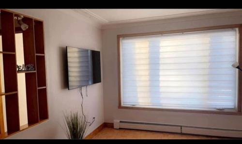 a living room with a window and a television at Private bedroom in Montréal