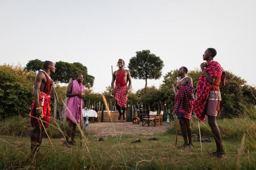 a group of people in dresses standing in a field at Enkusero Mara in Aitong